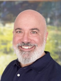 a bald man smiling in front of a painting