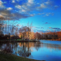 a lake surrounded by trees and clouds